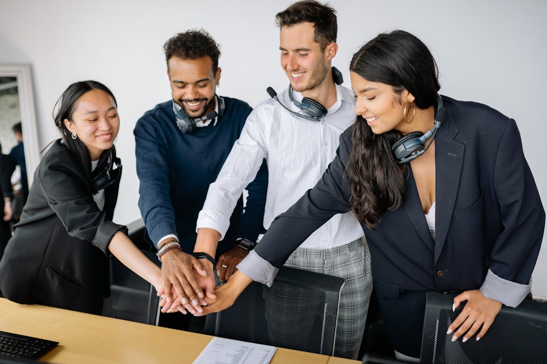 A team of people putting their hands together in a huddle.