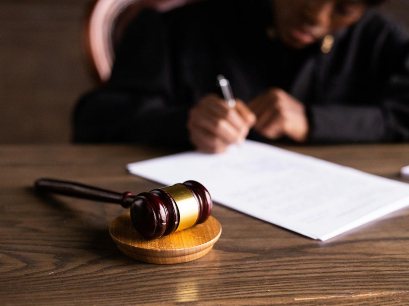Judge writing on paper with a gavel on the table