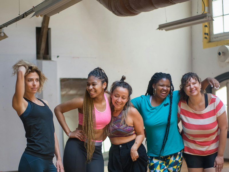 A group of women in a dance class laughing with each other