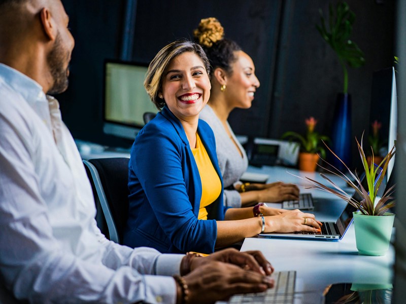A woman sat at a desk smiling with her co-worker